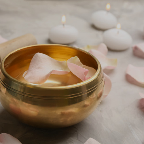 Golden bowl with rose petals surrounded by candles